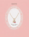 Necklace with cherry charm on a pink background